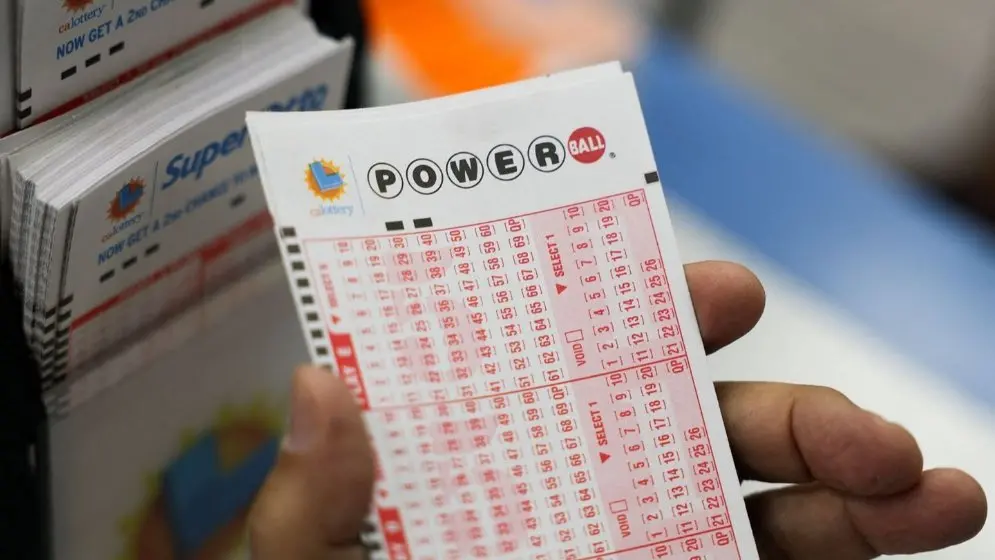 A hand holding a Powerball lottery playslip before a drawing